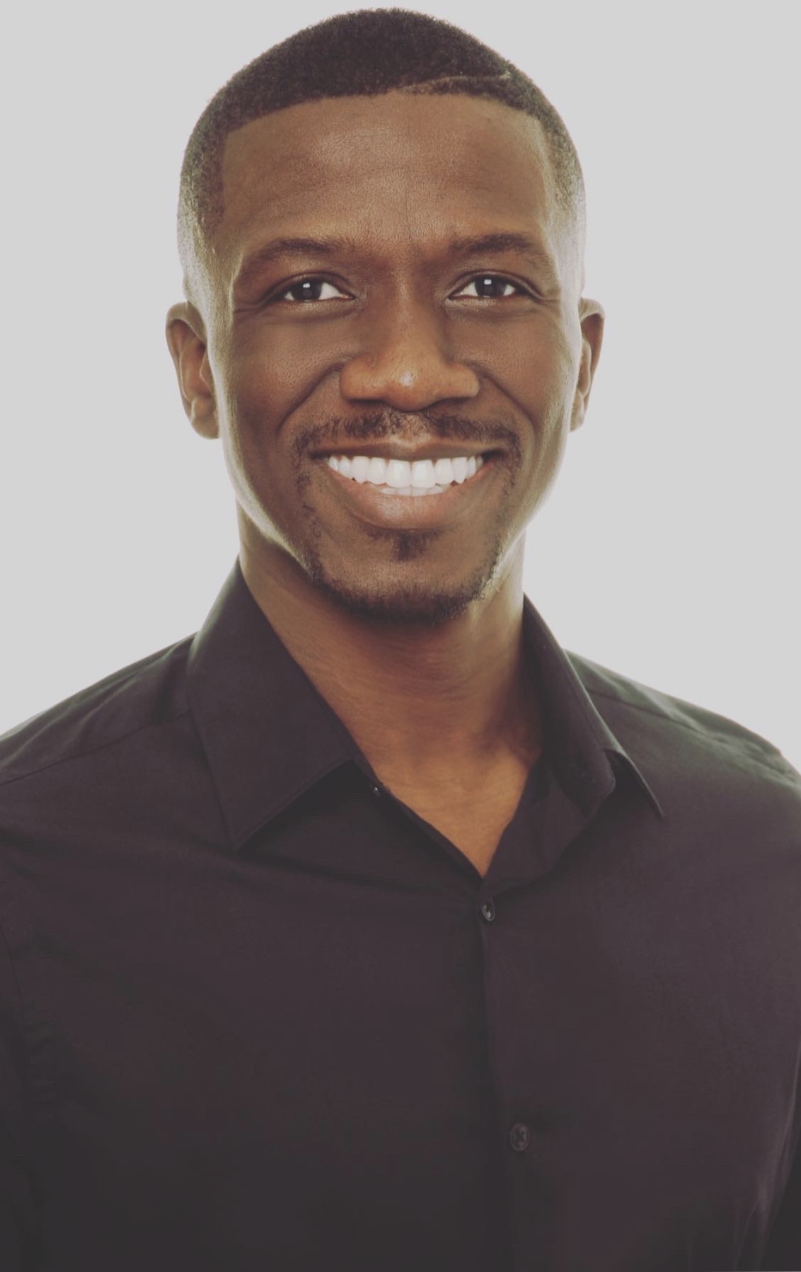 Kassim Alli-Balogun smiling in a black shirt